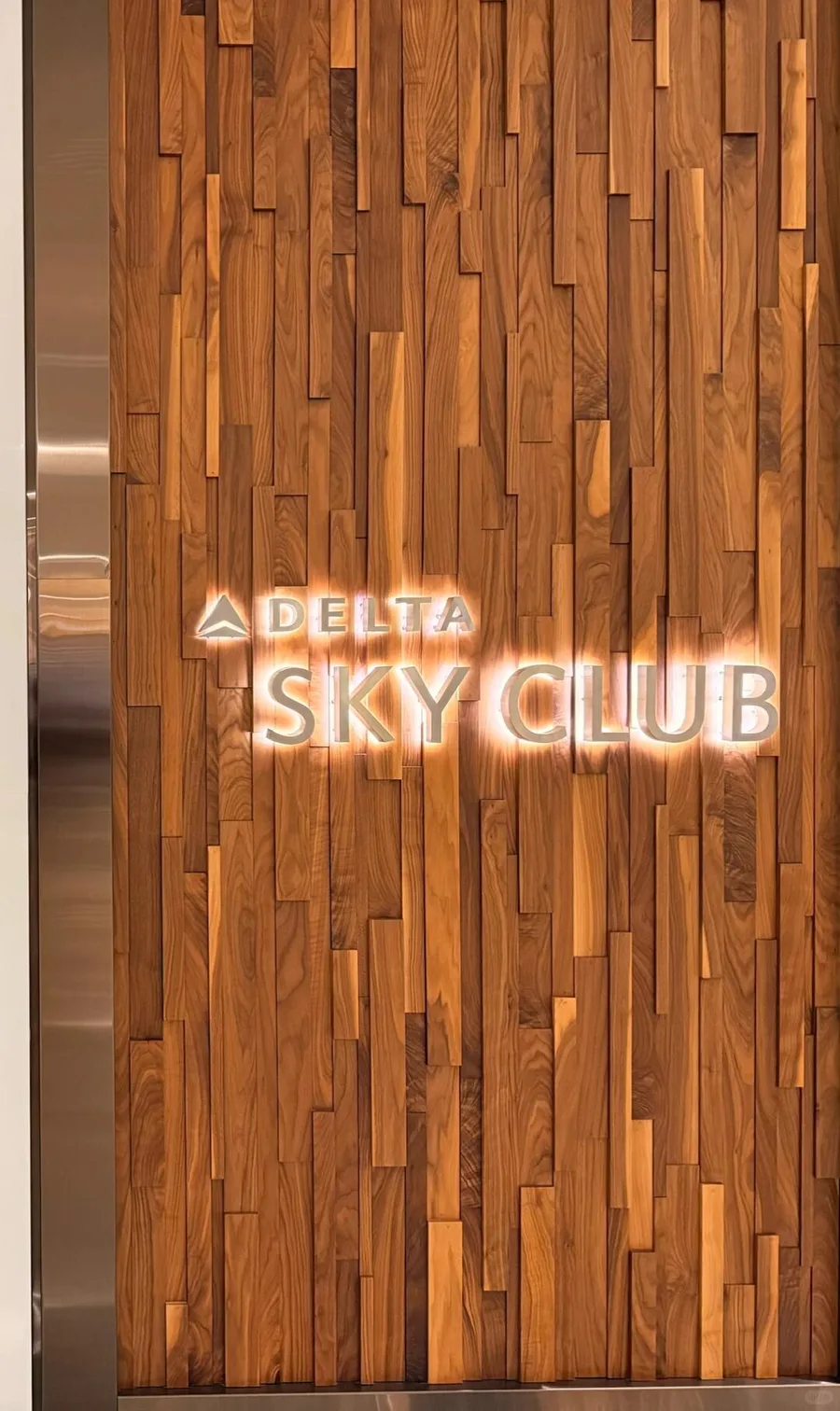 Illuminated Delta Sky Club sign on a textured wood wall at MSP