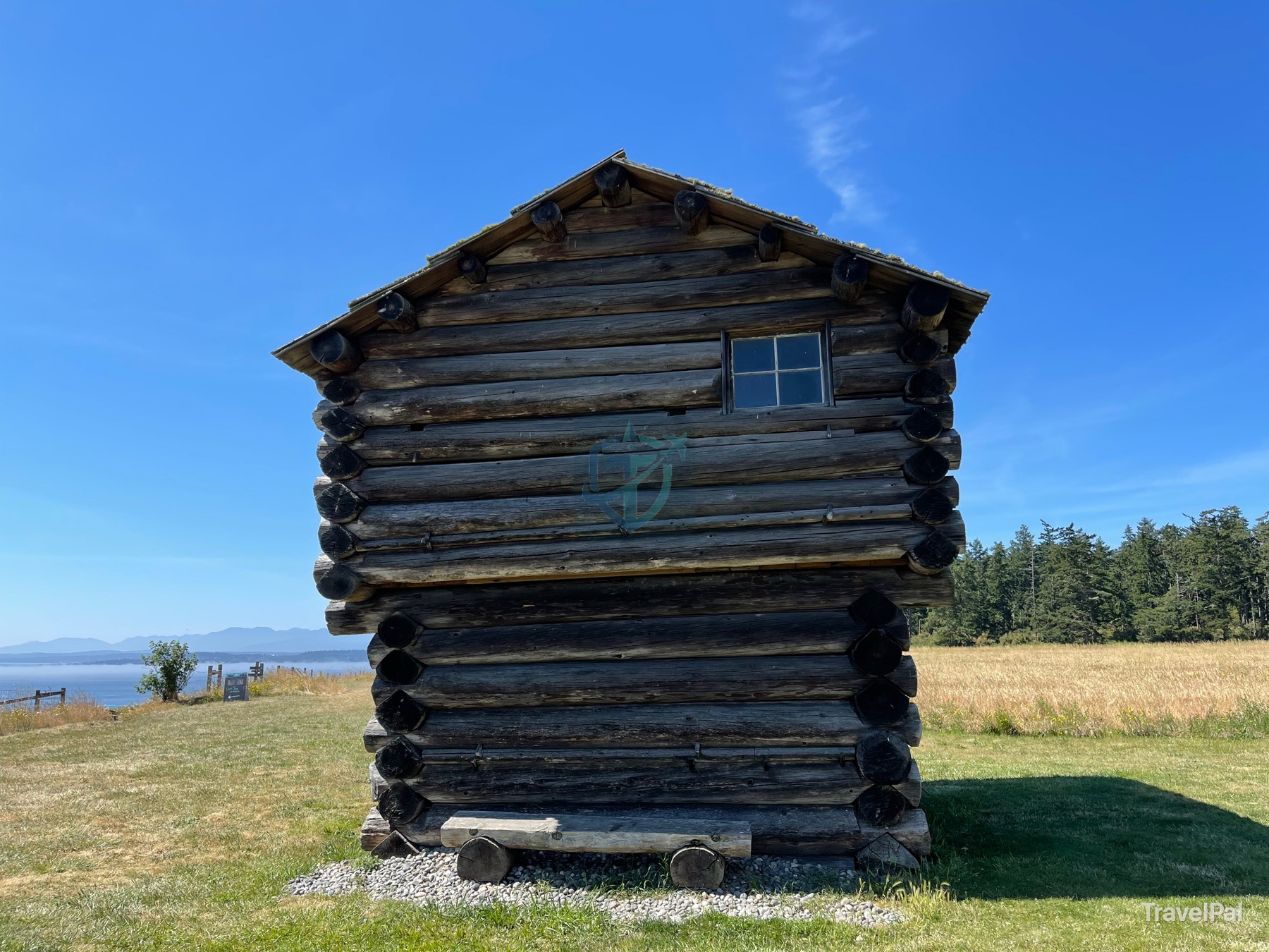 Weathered historic log structure standing beside a field and the water at Ebey’s Landing