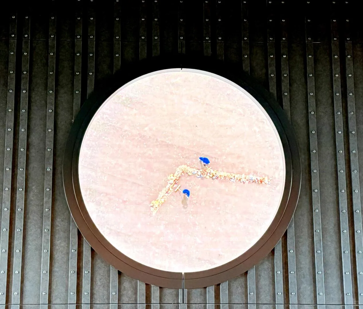 Large circular clock set into a dark wall at The Osaka Station Hotel